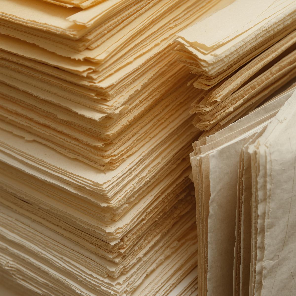 Stacks of fine printmaking and drawing paper with deckle edges.